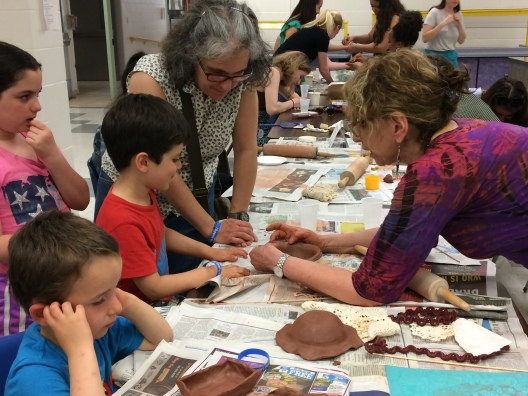 Local potter and Empty Bowls volunteer, Roberta Green helps a child with a clay project at the Empty Bowls event.