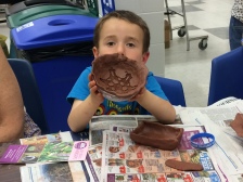 A young potter proudly displays his clay bowl.