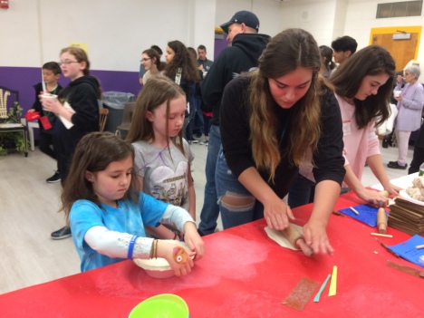 WVHS Empty Bowls Club members help young potters create clay bowls.